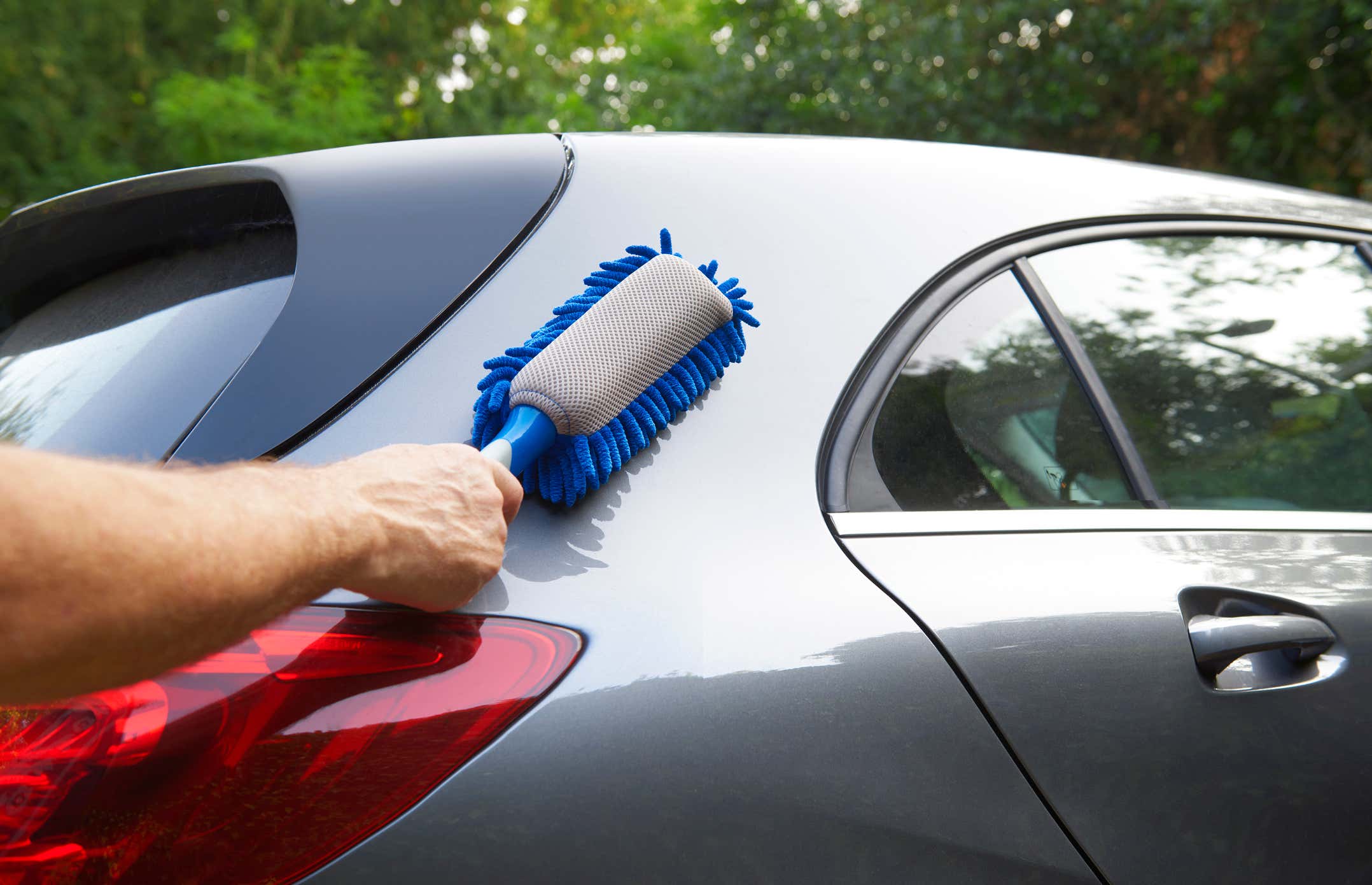 Outside of car being cleaned by hand with blue duster 汽车外面用蓝色的抹布手工清洁