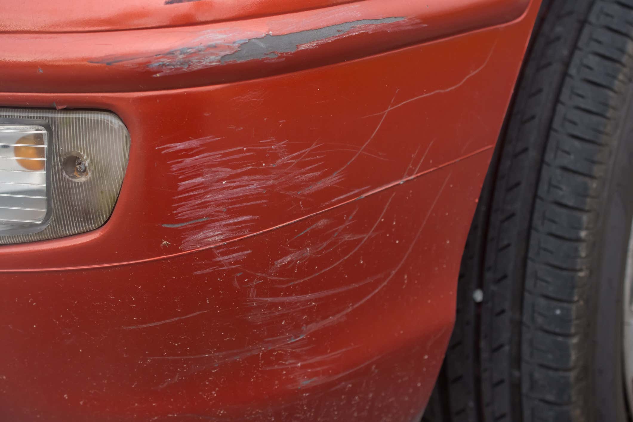 Red bumper car scratched with deep damage to the paint. 红色保险杠刮伤了涂料深深的伤害。
