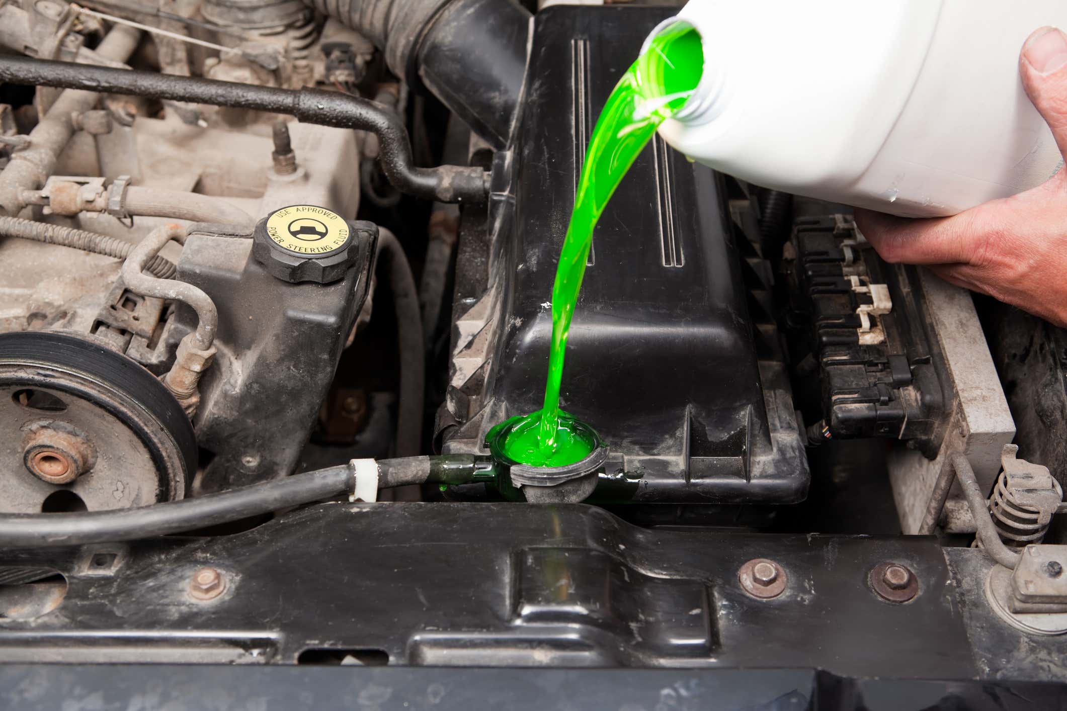 Someone pouring inorganic antifreeze into a vehicle’s radiator. 有人往汽车散热器里倒无机防冻剂。