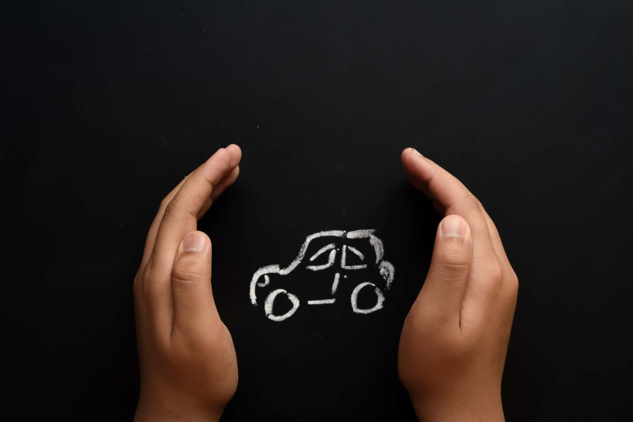 Hands “protecting” a car drawing. 手“保护”一辆汽车绘图。