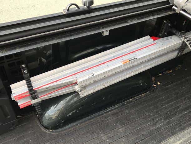 A folded ramp hanging on the side of a truck bed. 挂在卡车床沿上的折叠坡道。