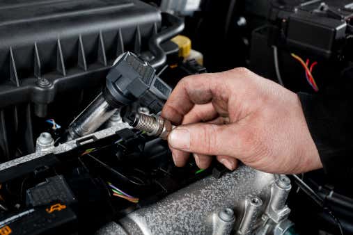 A mechanic working on a vehicle’s spark plugs. 工作在车辆的火花塞上的机械师。