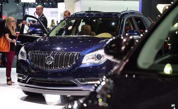 People inspect a Buick Enclave on display at the LA Auto Show 在洛杉矶车展上,人们正在观看一辆别克昂科雷