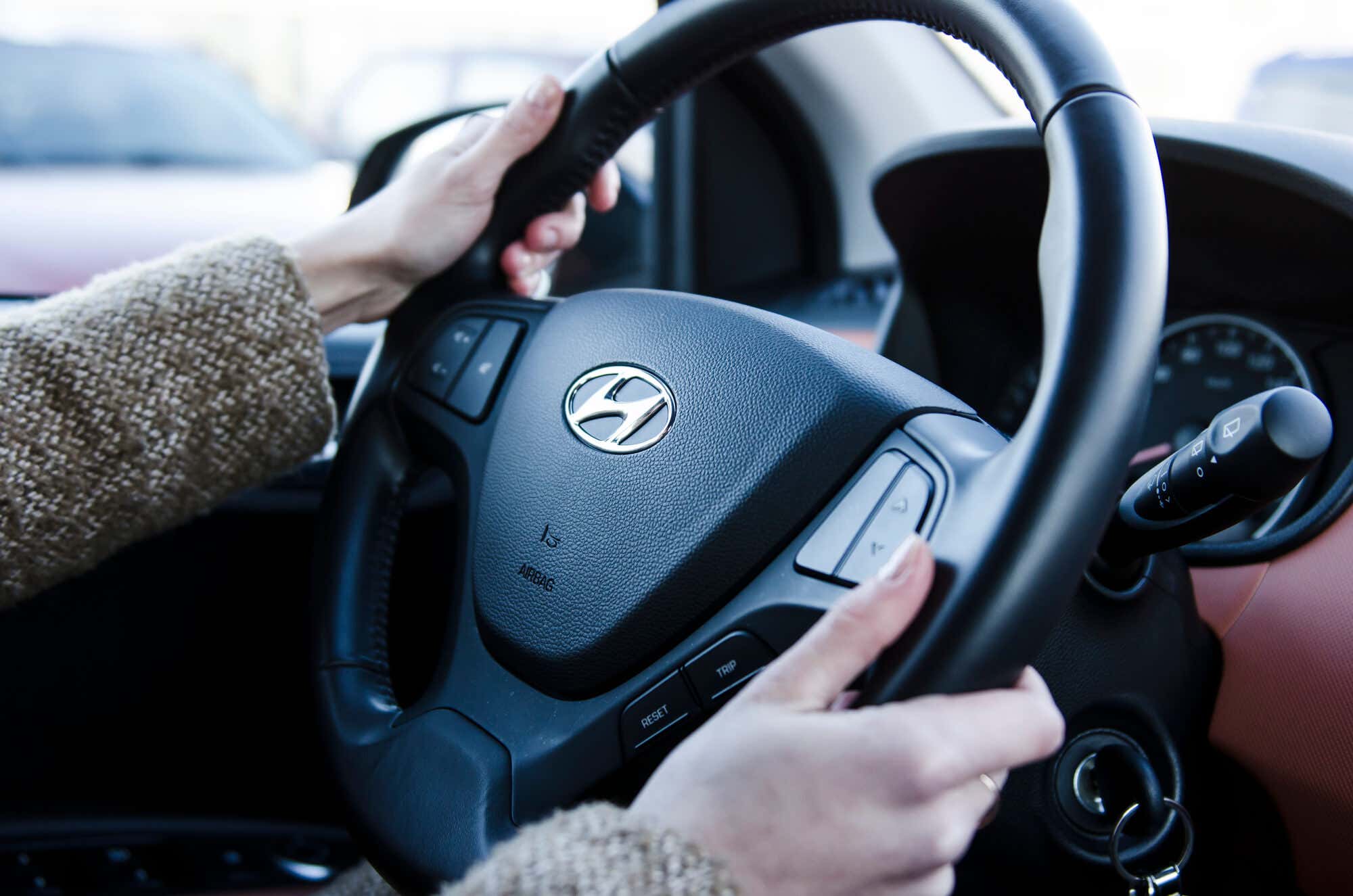 Hands holding steering wheel in hyundai car 拿着方向盘的手在现代汽车