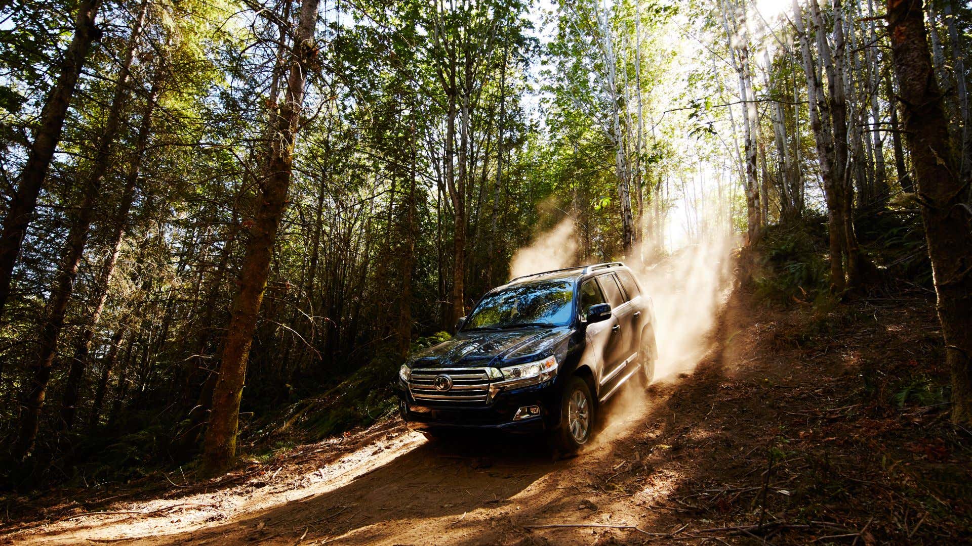 A 2020 Toyota Land Cruiser barrels down a dirt hill. 一艘2020年丰田陆地巡洋舰驶过一座土坡。