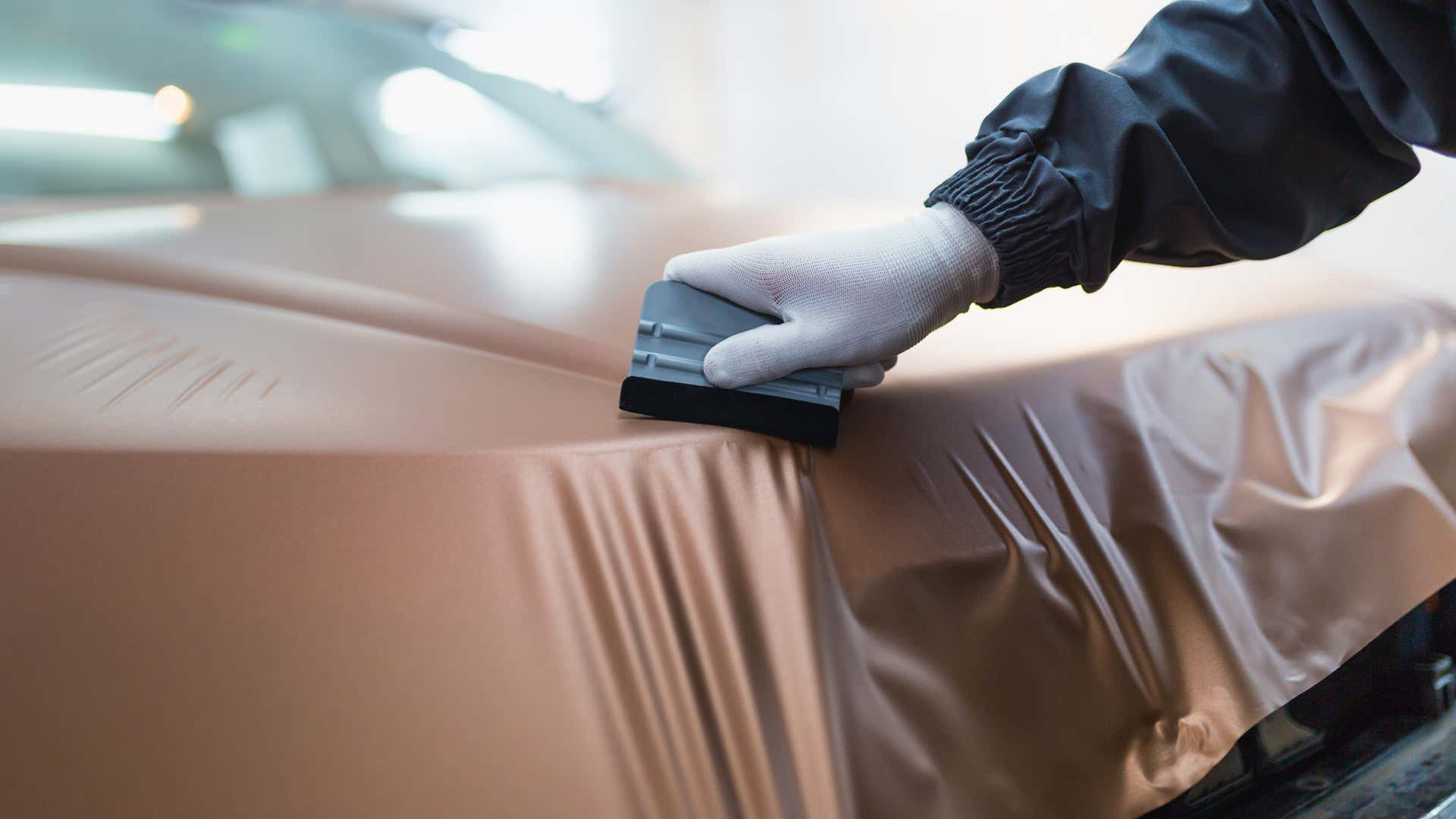 A installer uses a felt-edged squeegee to smooth out the vinyl. 安装程序使用毛毡边缘刮刀来平滑乙烯基。