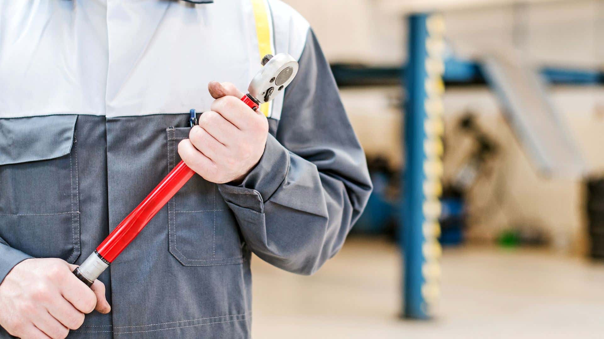 A man holds a torque wrench. 一个男人拿着扭矩扳手。