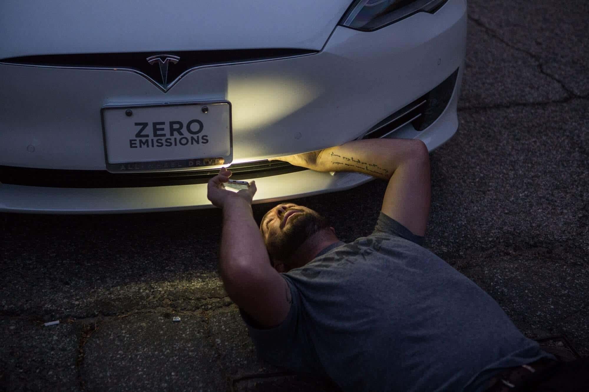 A guy looks underneath a Tesla Model S. 一个人在看特斯拉S型车下面。