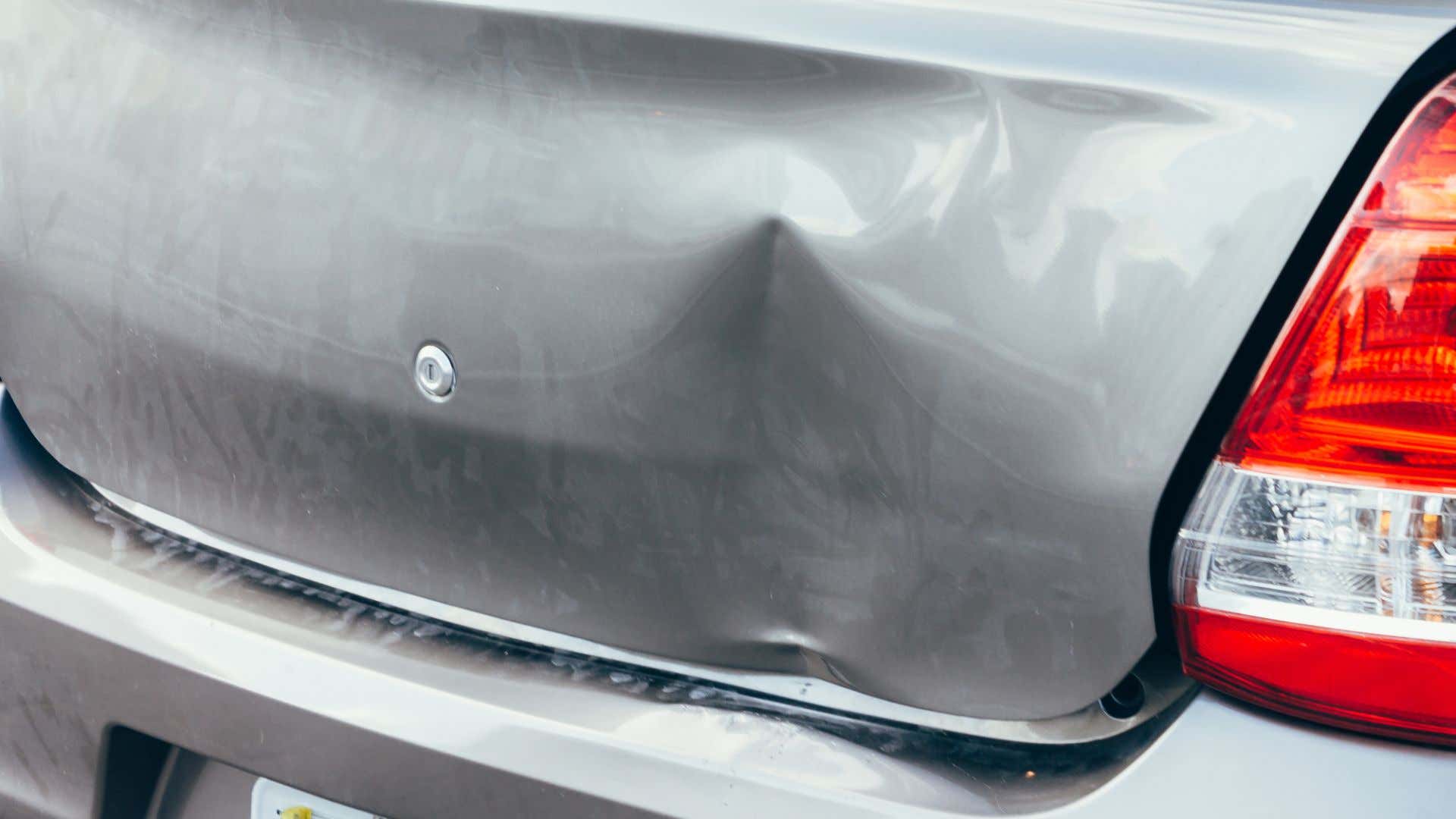 A large dent in a car's trunk. 一辆车厢里的一个大凹痕。