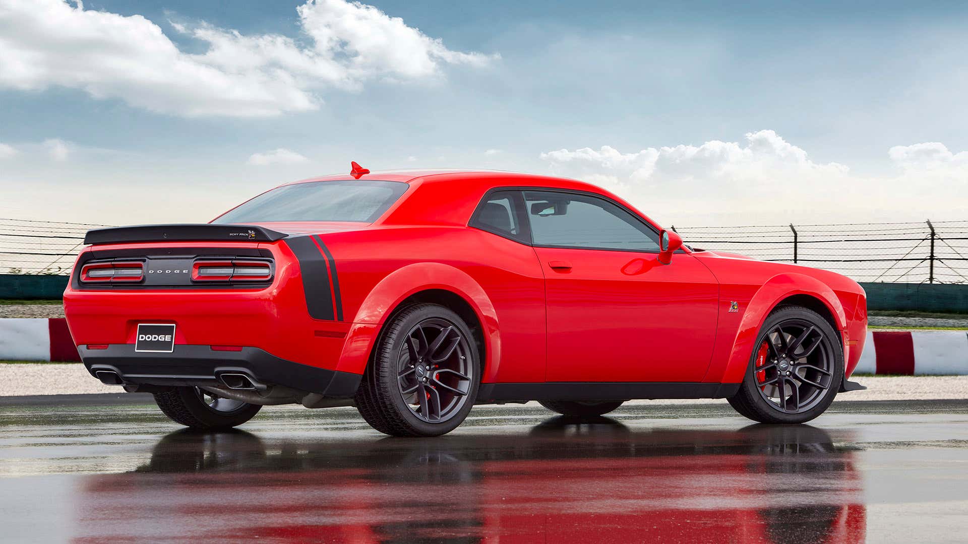 The rear end of a red 2021 Dodge Challenger Scat Pack with. 一辆红色2021道奇挑战者猫包的尾部。