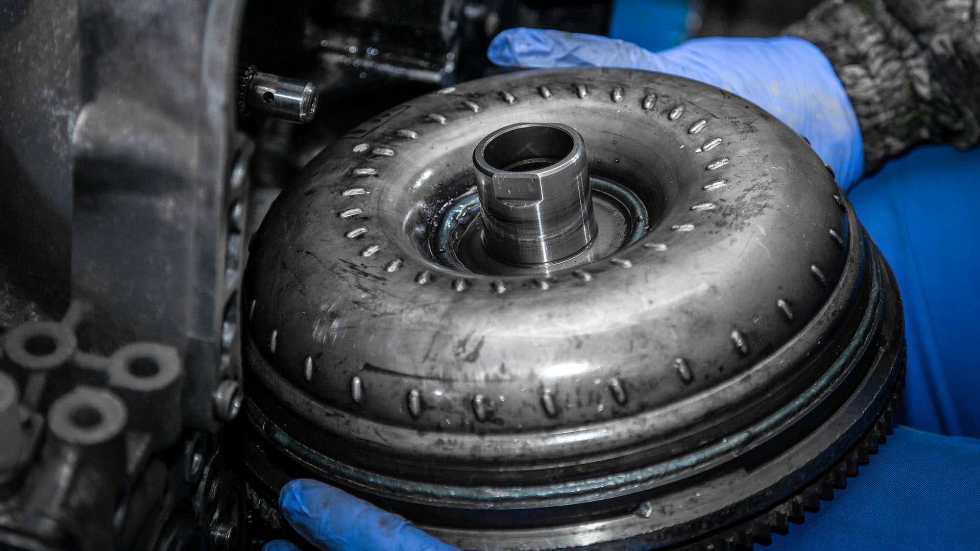 A mechanic removes a torque converter from the transmission. 机械师从变速器中移除扭矩转换器。