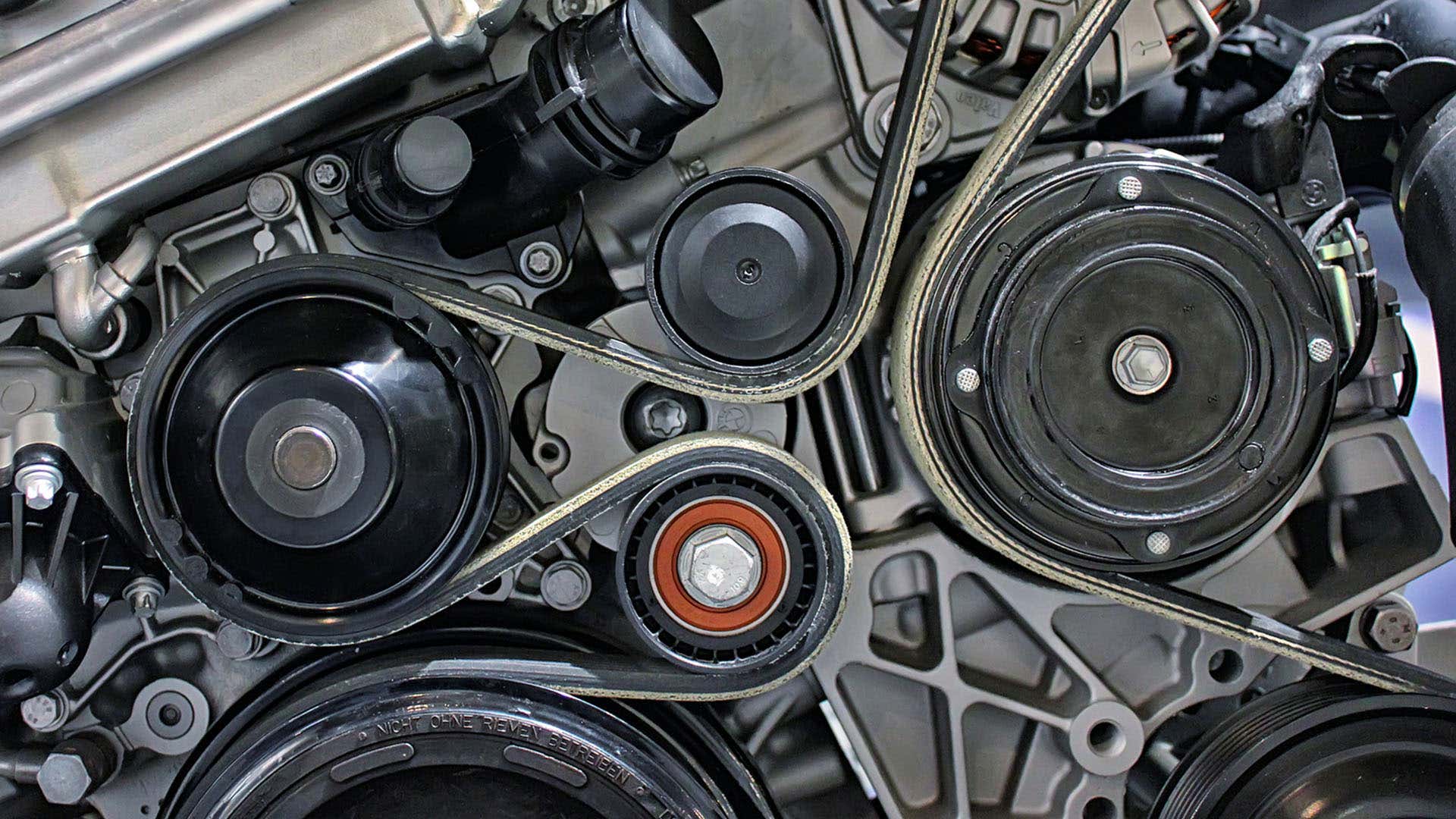 A closeup of an engine and its serpentine belt wrapping around pulleys. 发动机及其缠绕在滑轮上的蛇形皮带的特写镜头。