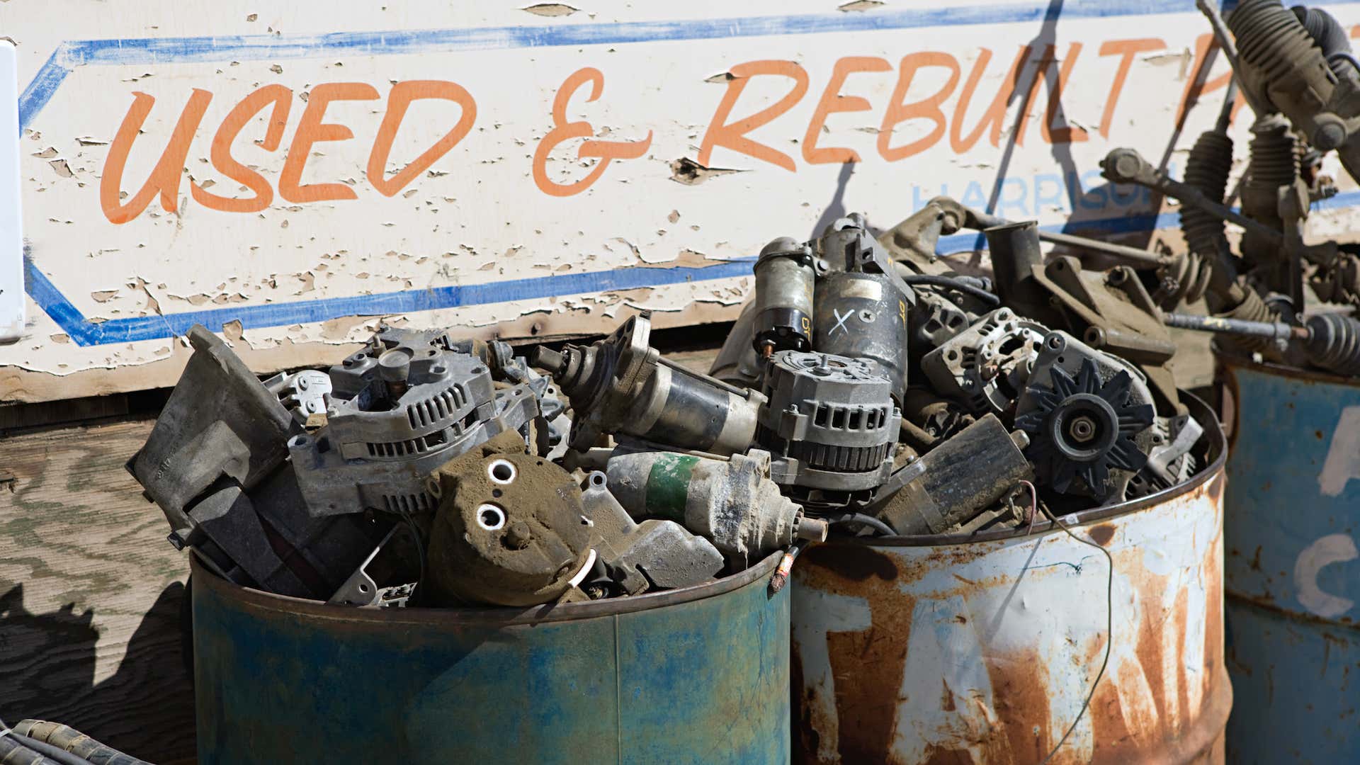 Two metal tanks full of scrapped parts such as alternators and starters. 两个金属罐装满了废弃的部件,比如发电机和启动器。