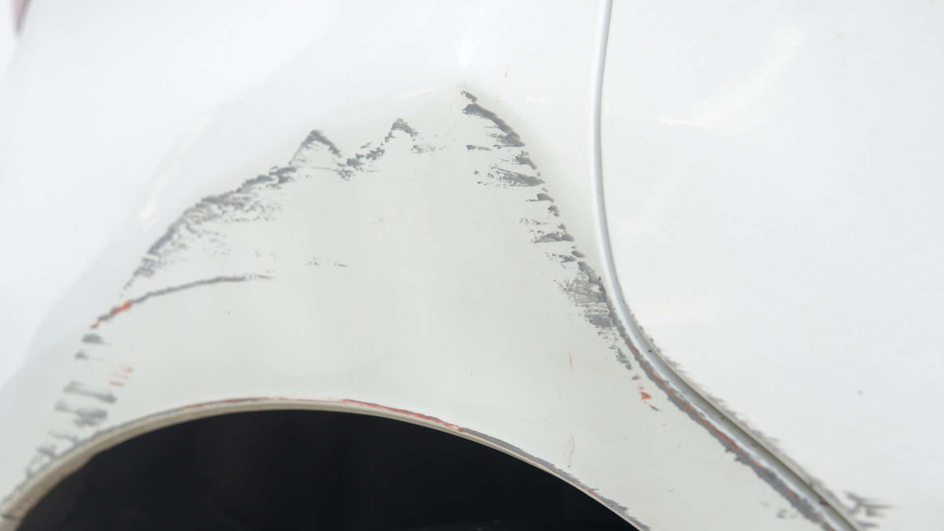 A white car scratched around the wheel well. 一辆白色的汽车在轮舱周围刮来刮去。