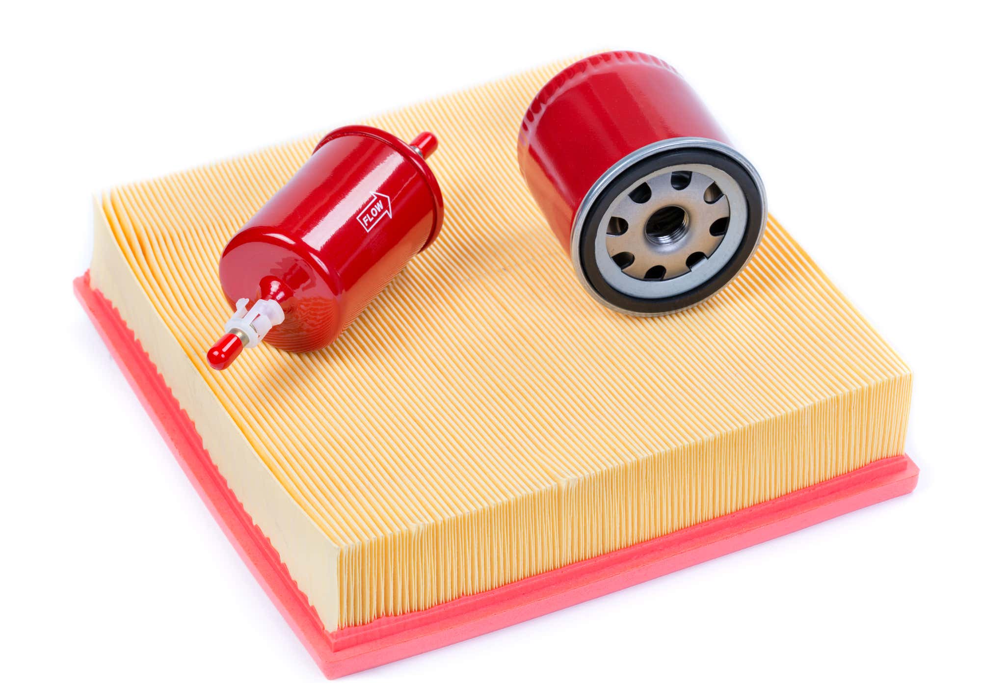 A red fuel filter and red oil filter sit on top of an off-white air filter. 红色燃油滤清器和红色滤油器坐在灰白色空气过滤器的顶部。