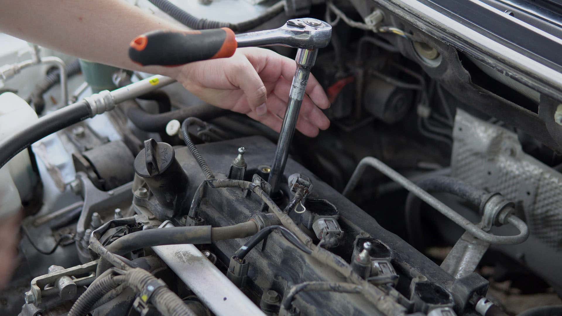 A mechanic removes spark plugs with a socket wrench. 机械师用套筒扳手去除火花塞。