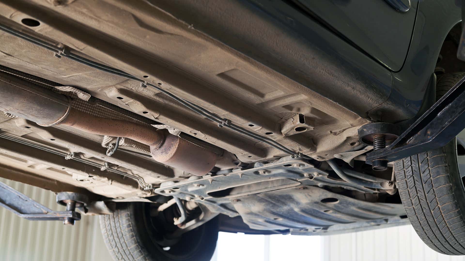 The exhaust system is tightly tucked underneath a car. 排气系统被紧紧地塞在汽车下面。