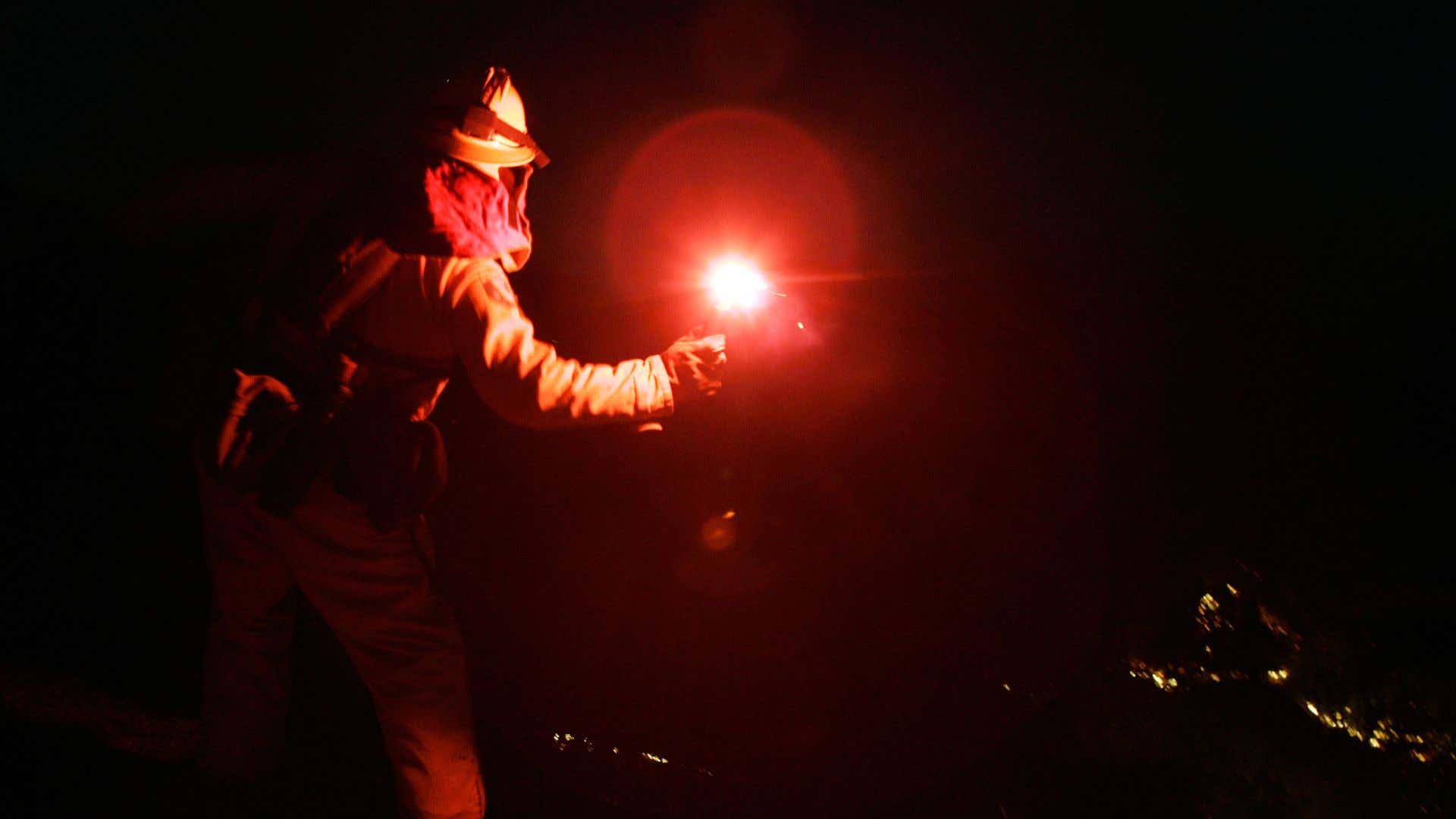 A firefighter throwing a flare. 一名消防队员在投掷照明弹。