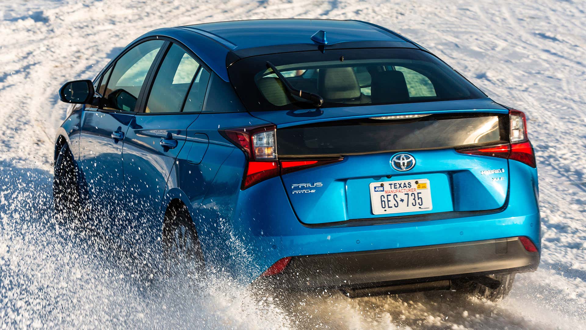 A blue Toyota Prius with AWD-e driving on white snow. 与awd-e驾驶在白色雪的蓝色丰田普锐斯。