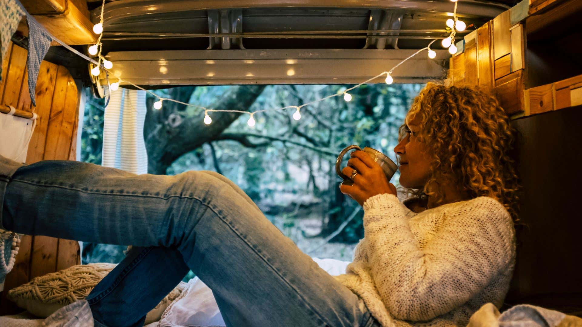 A woman enjoying some coffee in the morning from her van. 一个女人早上在她的面包车里喝咖啡。