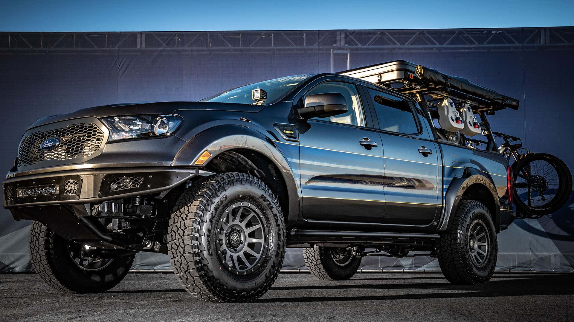An adventure-customized Ford Ranger with chunky tires and a bike rack. 一个冒险定制的福特Ranger与厚实的轮胎和自行车架。