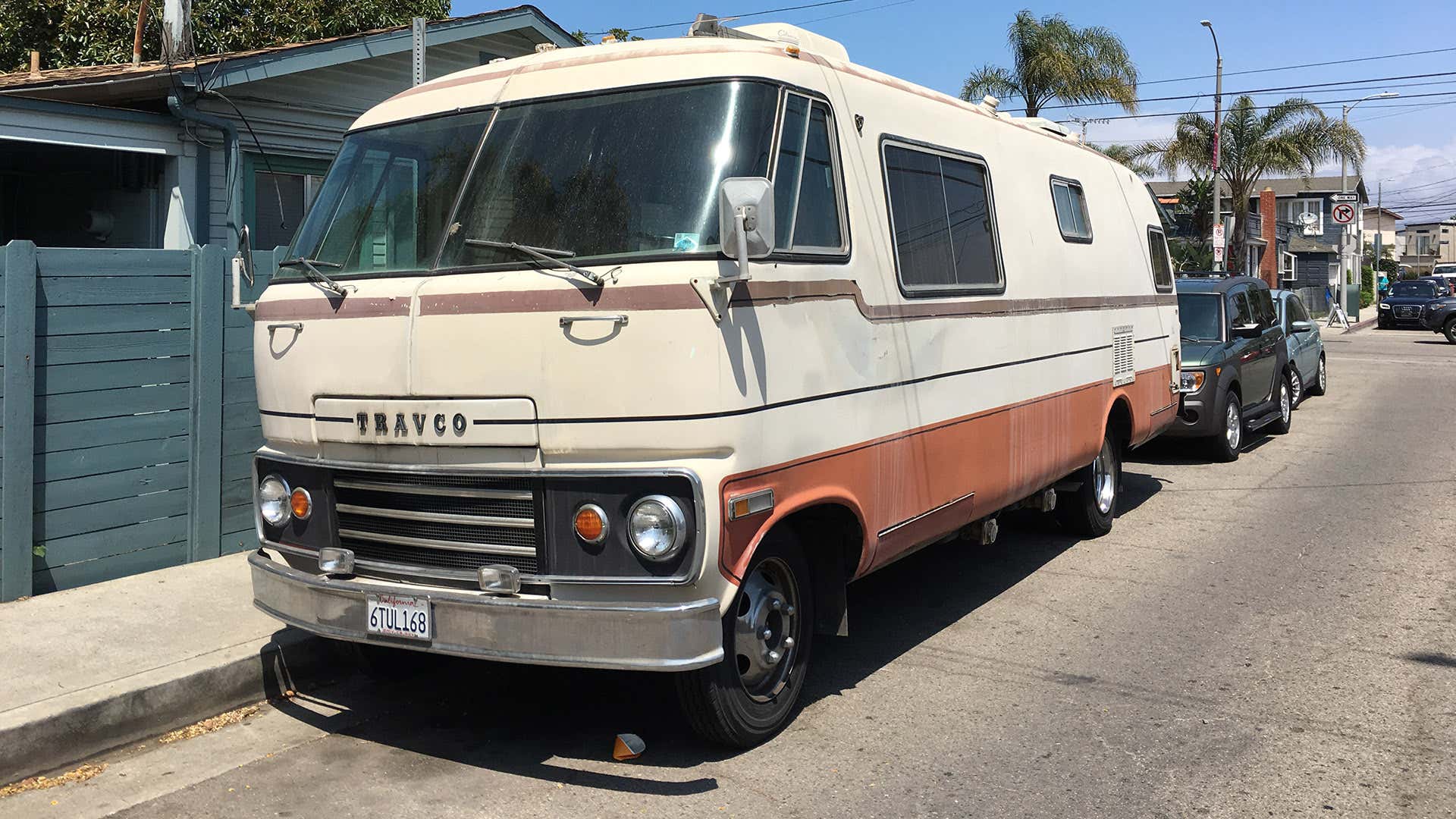A Travco RV parked on the street. 一个travco rv停在街上。