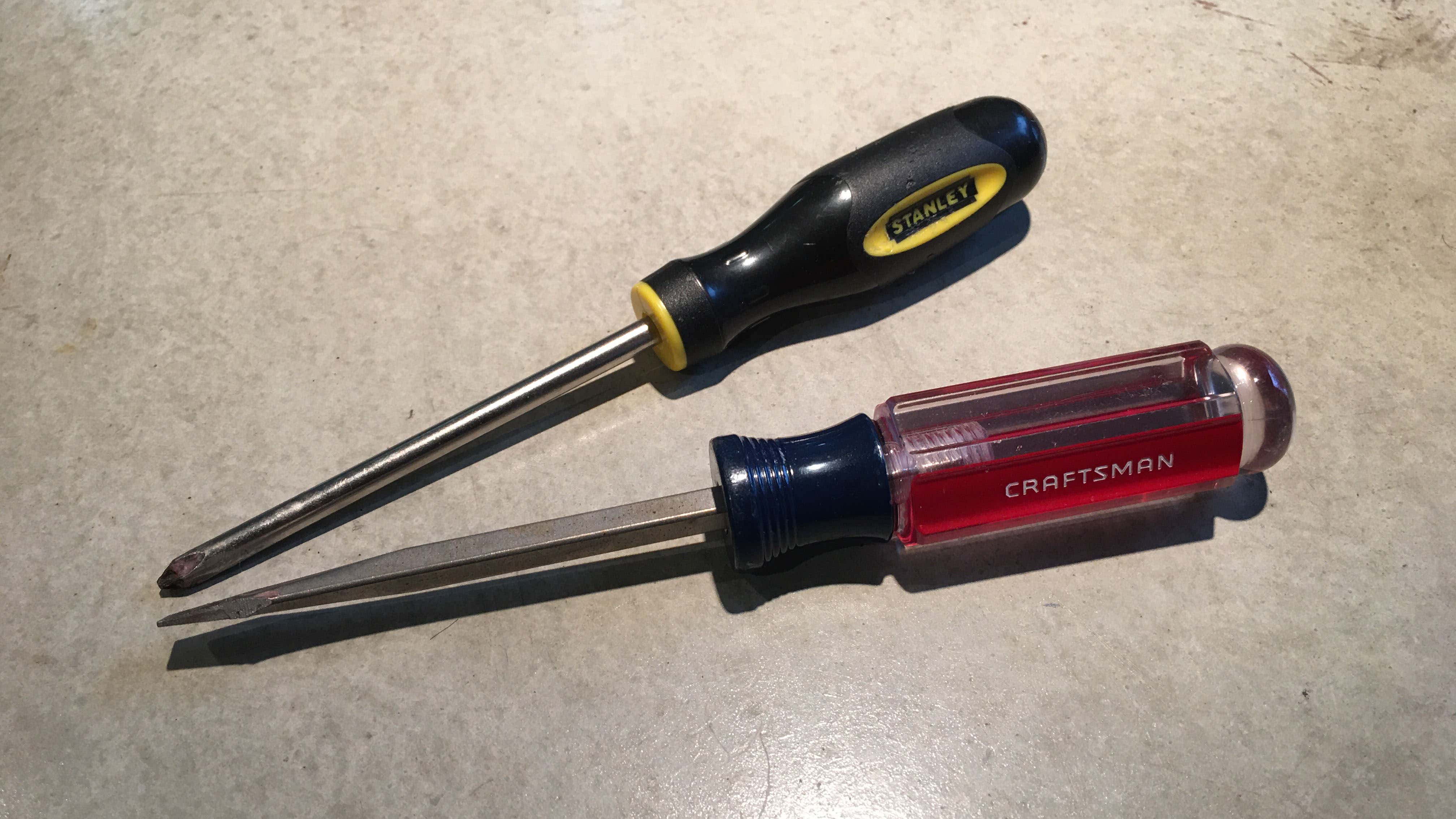Craftsman and Stanley screwdrivers on a concrete background. 工匠和斯坦利在混凝土背景上用螺丝刀。