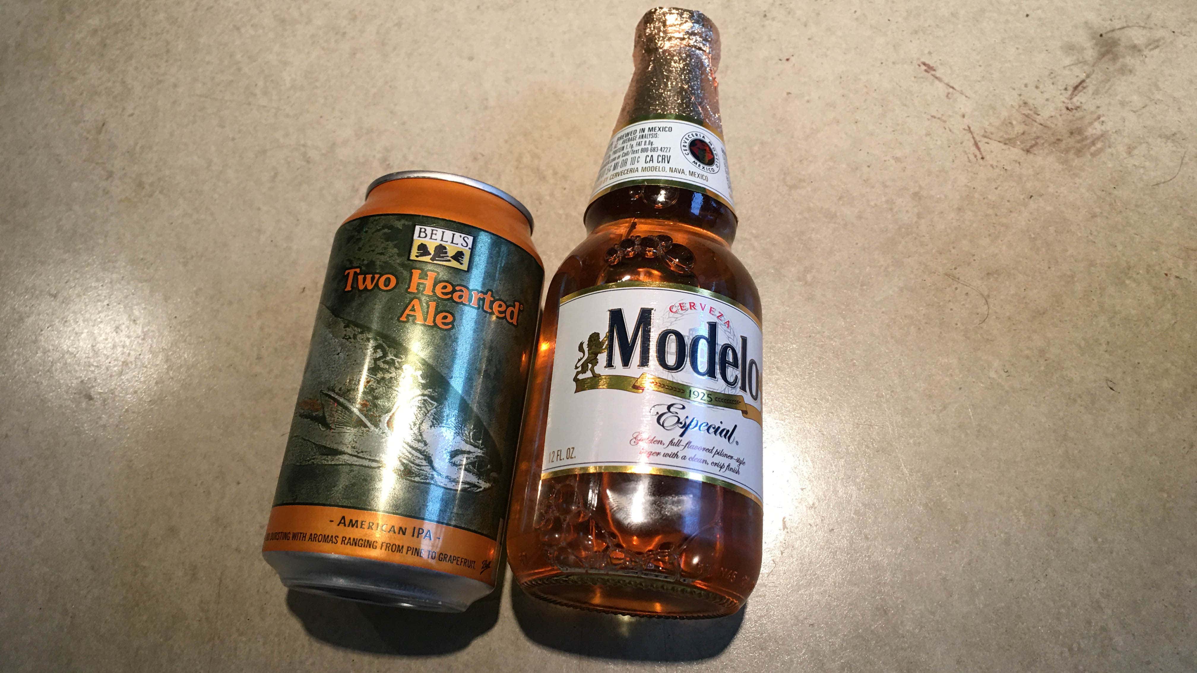 A Bell's Two Hearted Ale and a Modelo on concrete. 一杯钟形双心啤酒和一杯混凝土模型啤酒。