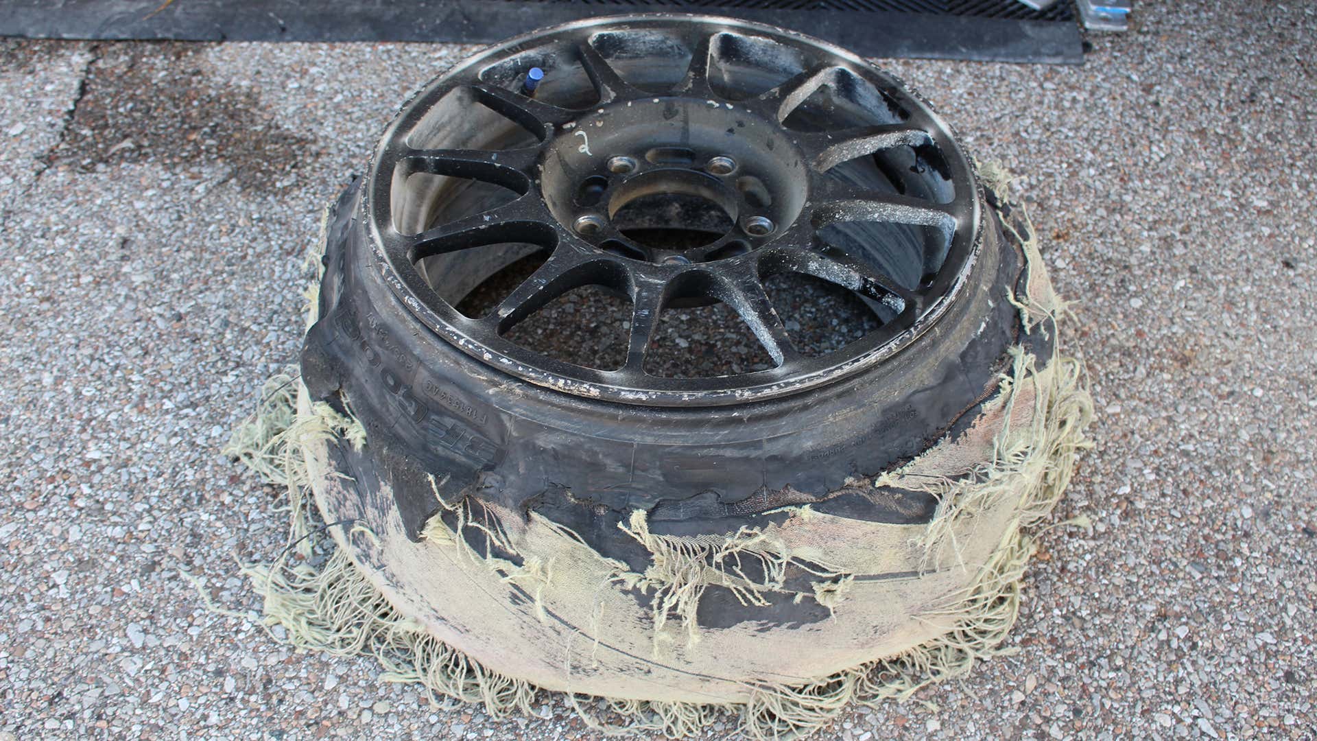 A shredded tire on a racing wheel. 在赛车轮上的撕裂的轮胎。
