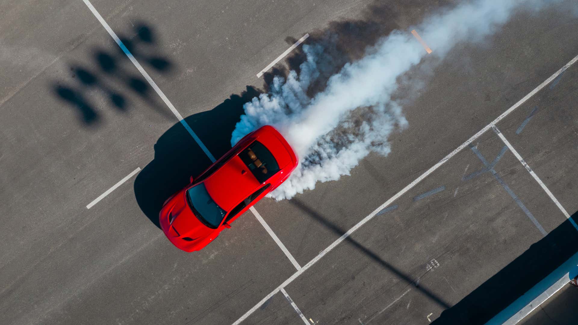 A Dodge Charger SRT Hellcat leaves billows of smoke in a parking lot after a burnout. 在倦怠之后,道奇充电器SRT Hellcat留下了停车场的烟雾。