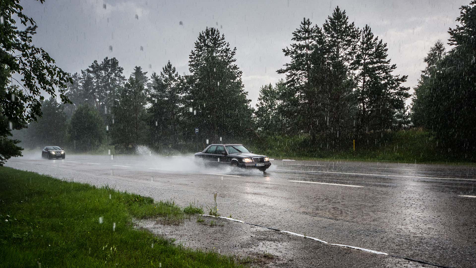 A Mercedes-Benz sedan driving in the rain. 一辆奔驰轿车在雨中行驶。