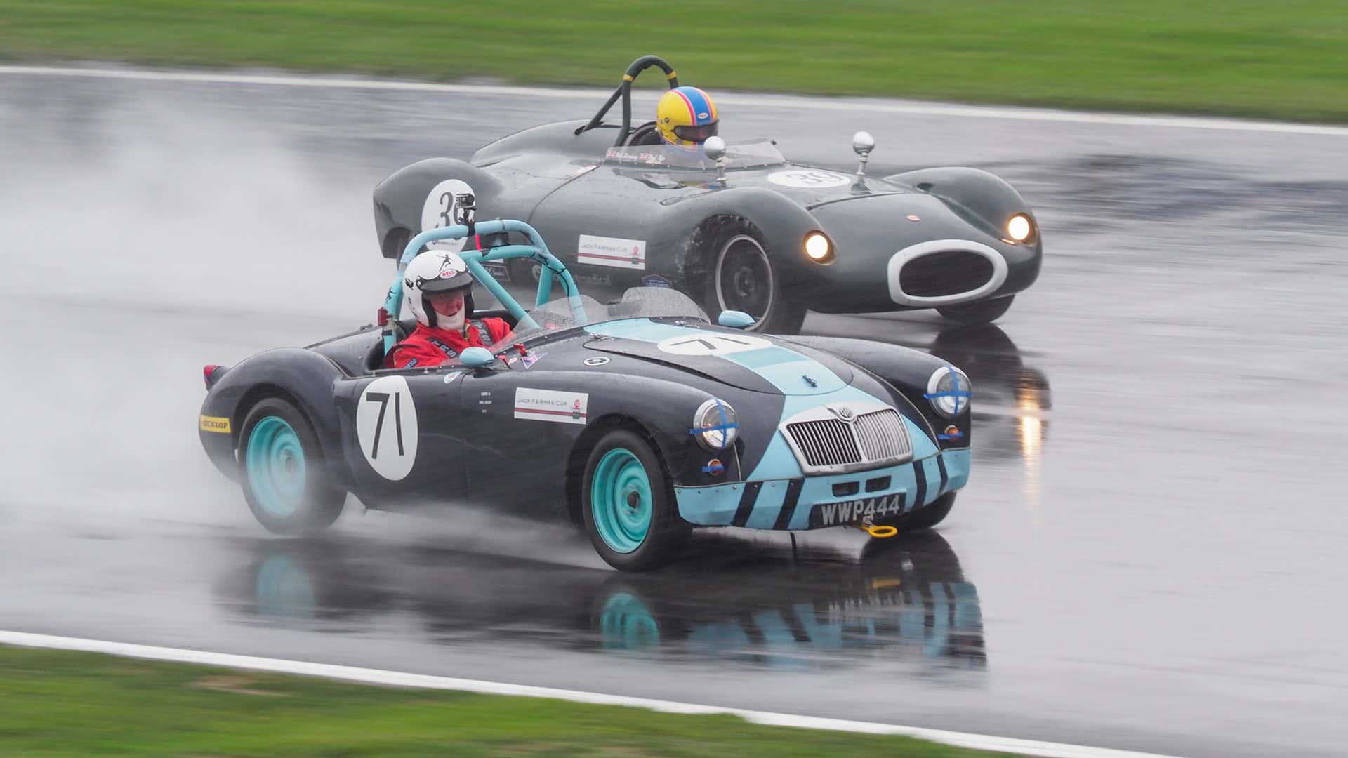 Classic racecars driving in the wet. 经典的赛车在潮湿的环境中行驶。