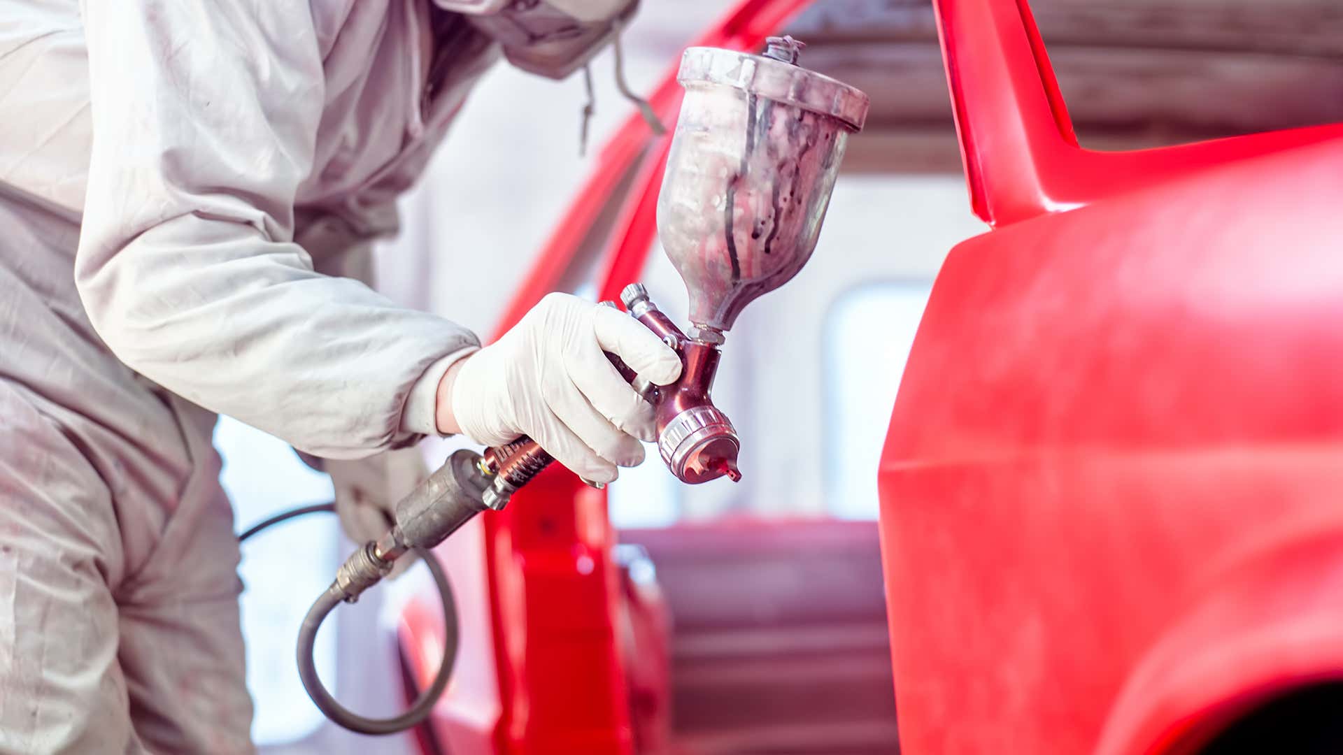A person uses a pneumatic paint sprayer to paint a car. 一个人用气动喷漆器给汽车喷漆。