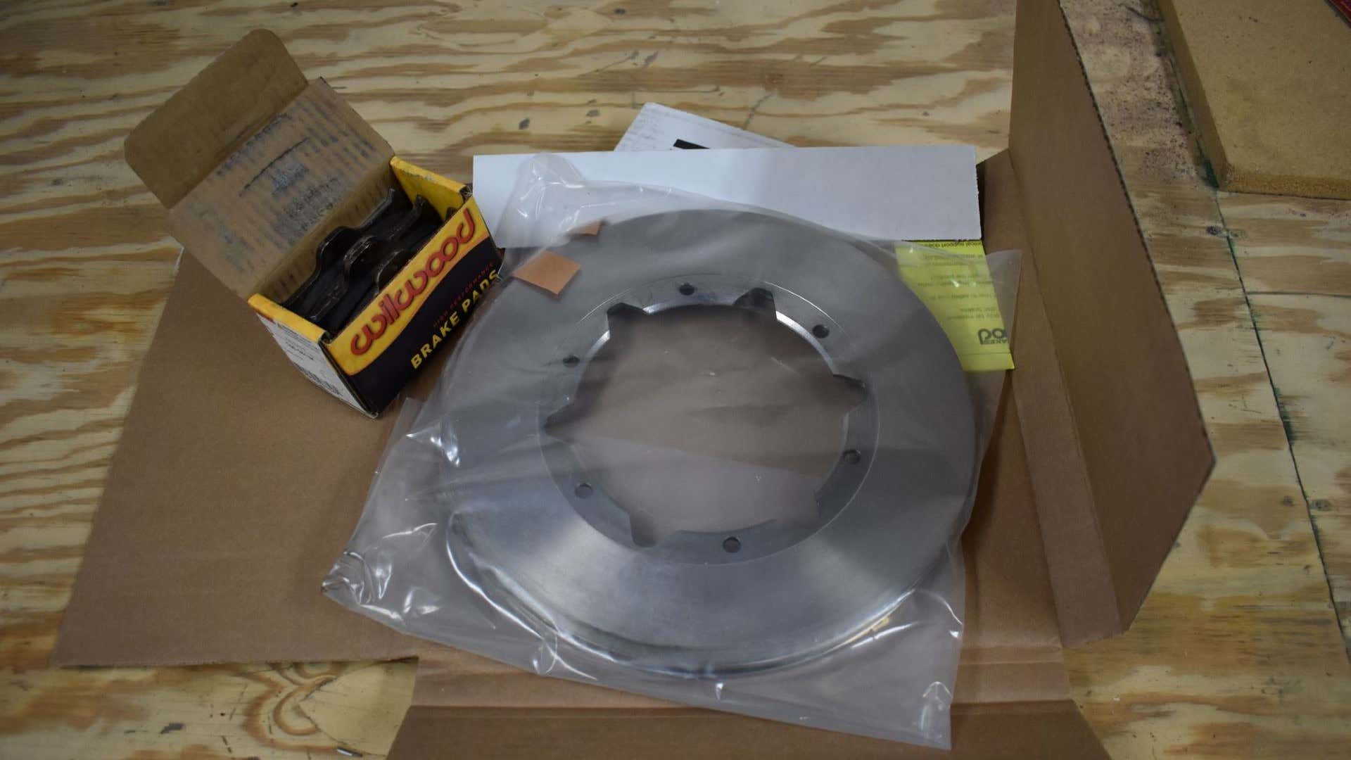 New brake pads and brake rotors in a box on a wooden table. 新的刹车垫和制动器在一个箱子在一张木桌上。