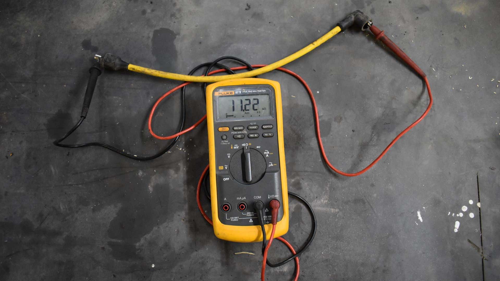 A multimeter testing a spark plug wire. 万用表测试火花塞线。