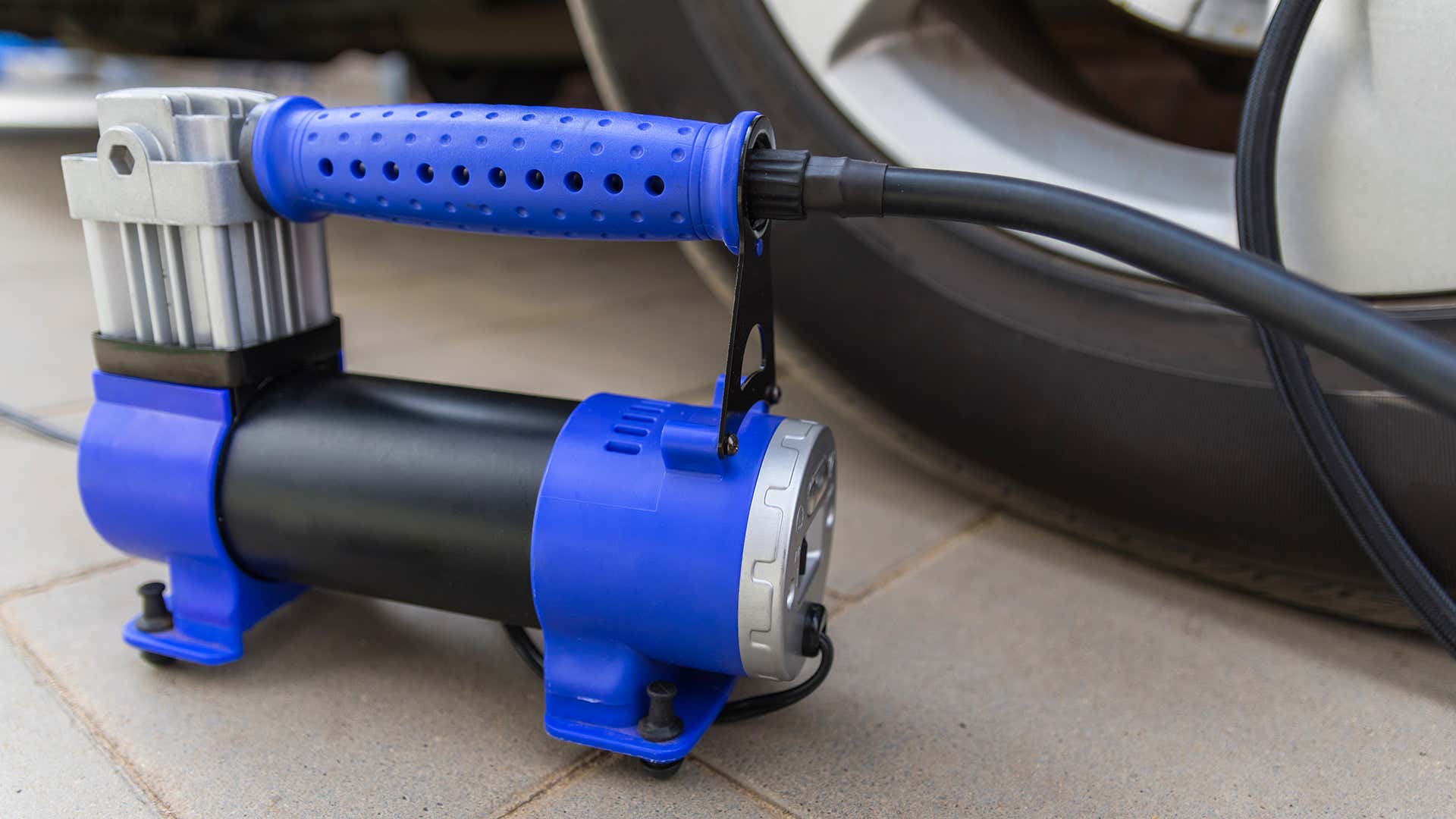 A blue tire inflator next to a wheel. 在轮子旁边的蓝色轮胎充气器。
