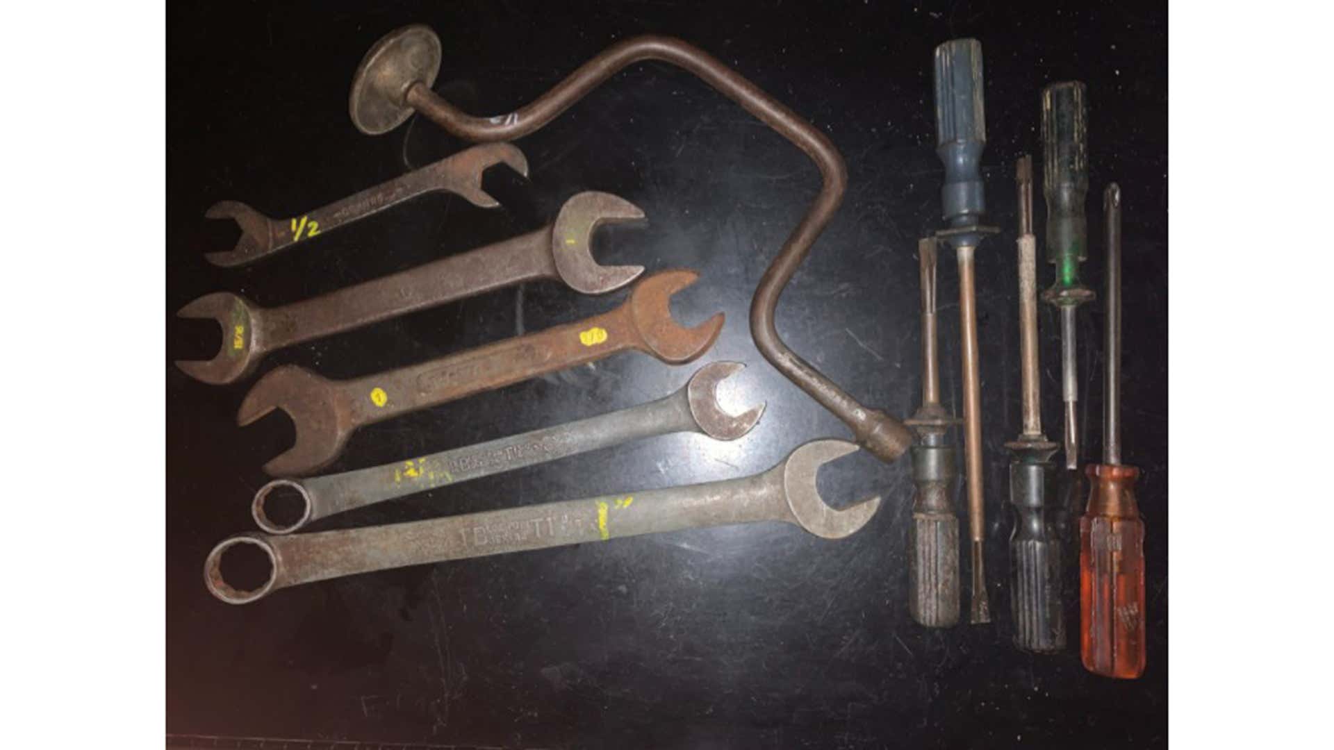 Old wrenches and screwdrivers on a black table. 黑色的桌子上放着旧扳手和螺丝刀。