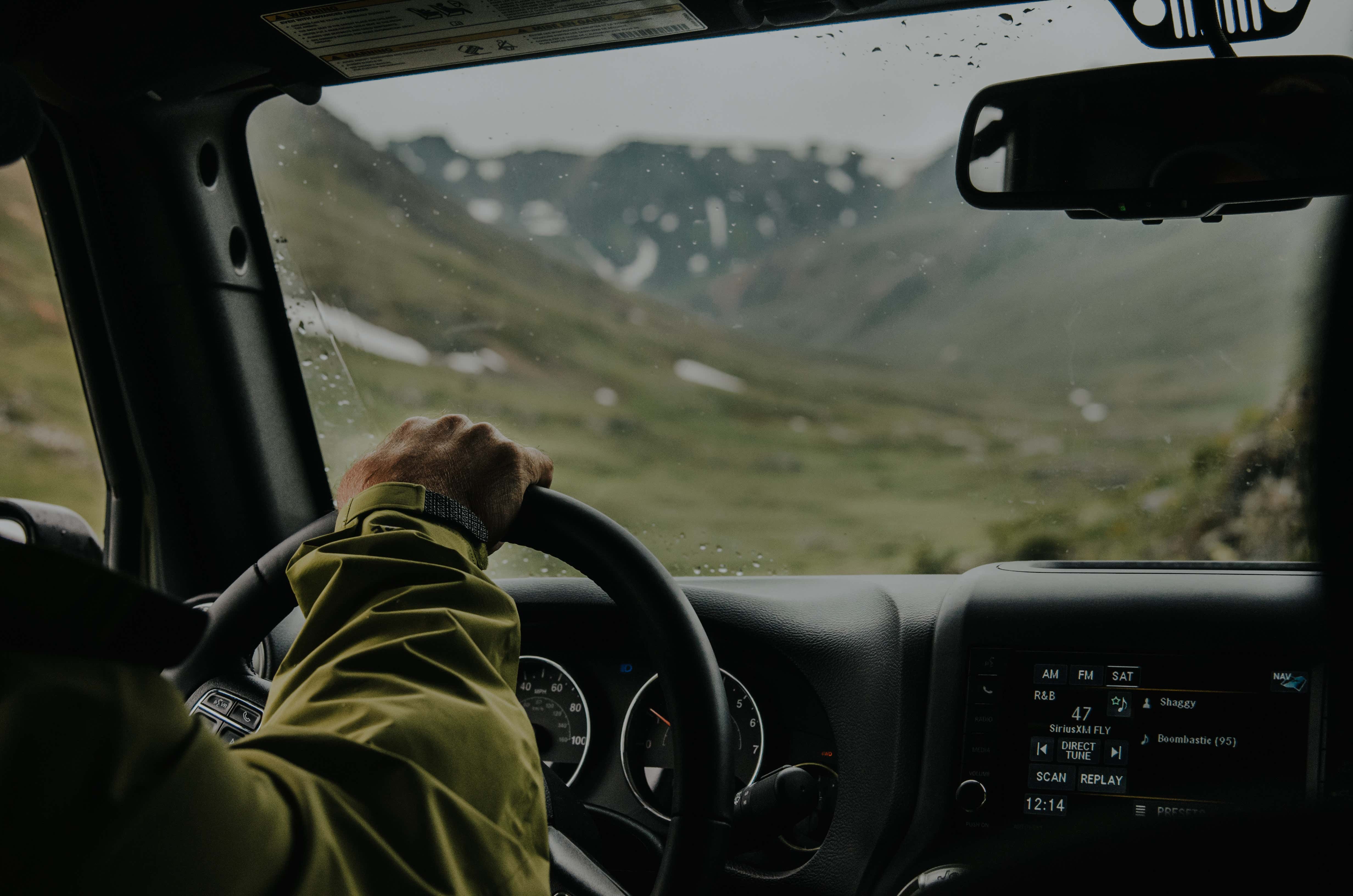 一个人驾驶着他们的汽车穿过一系列的绿色山脉