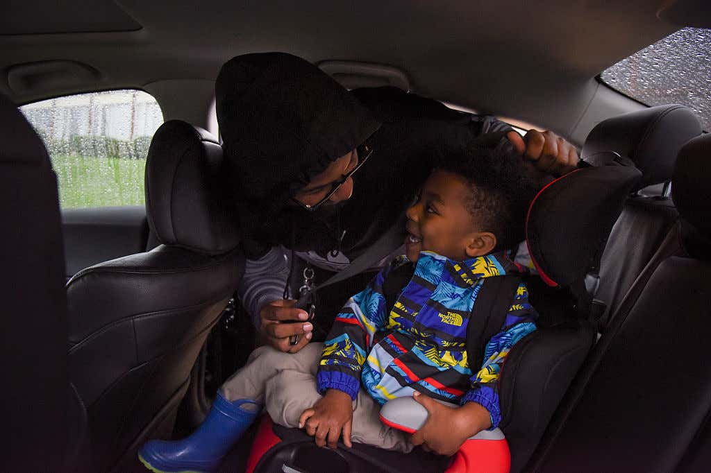 一名妈妈在他的汽车座位上搭起她的小男孩。