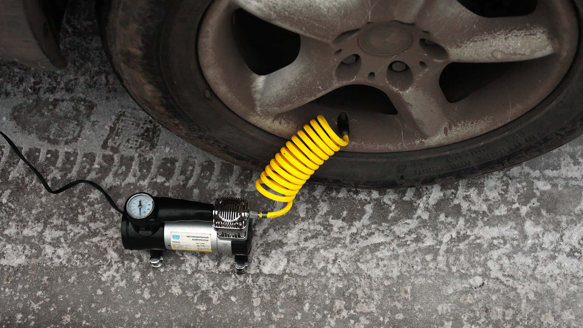 黑色轮胎打气筒，黄色软管卷连接到宝马车轮和轮胎。