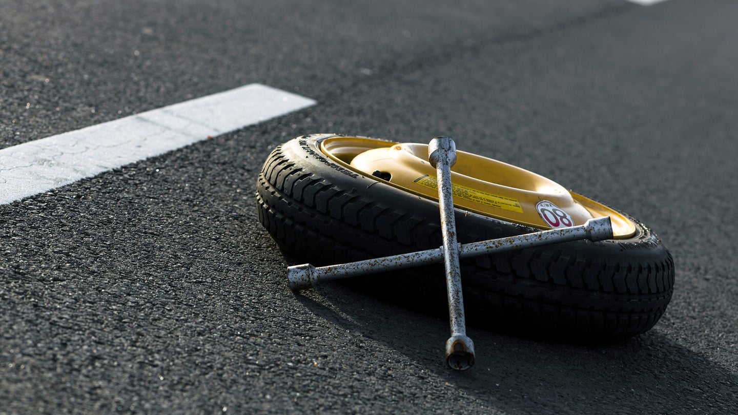 一条四路凸耳扳手坐在路中间的备用轮胎上。